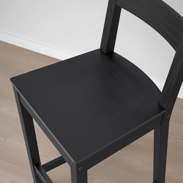 Black wooden stool with curved backrest, solid construction, comfortable seat.