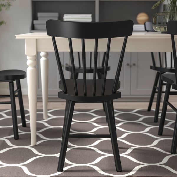 Black spindle chair with rounded design for comfort; sturdy wooden frame, suitable for indoor use.