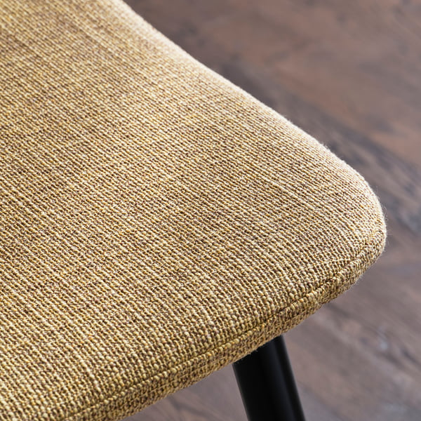 Close-up of a modern, upholstered chair with a textured fabric seat and metal legs, highlighting comfort and durability.