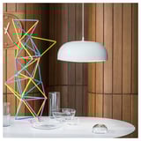 Modern dining setup with NYMÅNE lamp, geometric decor, and wooden panel wall.