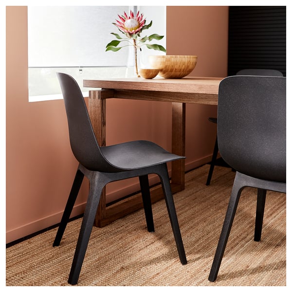 Modern dining setup with two dark grey ODGER chairs and a wooden table, featuring a stylish, curved design with a textured finish.