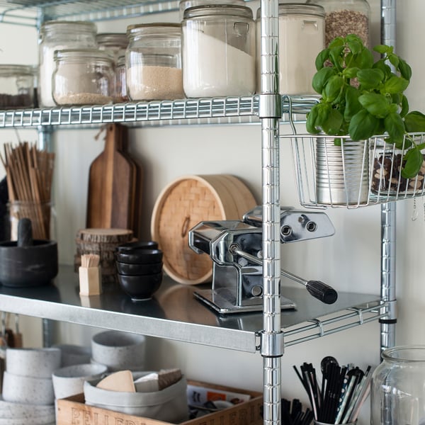 Modern metallic kitchen shelf with jars of ingredients and baskets.