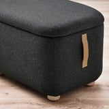Oskarhamn footstool with storage, dark fabric, leather handles, wooden legs. Comfortable and stylish for extra seating or resting feet.