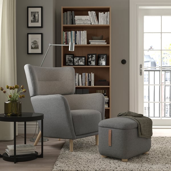 Cozy living room: gray OSKARSHAMN wing chair & ottoman, wooden legs, plus bookshelf & side table.
