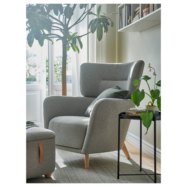 Grey chair & footrest, plant, book table. Cozy reading nook with natural decor.