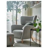 Grey chair & footrest, plant, book table. Cozy reading nook with natural decor.
