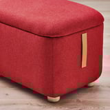 Red fabric footstool with storage, wooden legs, and leather handle.