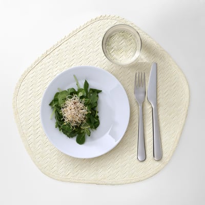 White plate with green salad on woven mat. Inset with fork and knife, small glass.