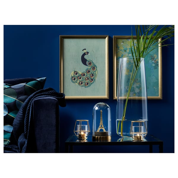 Blue living room with peacock art, plant, black couch, golden decor.