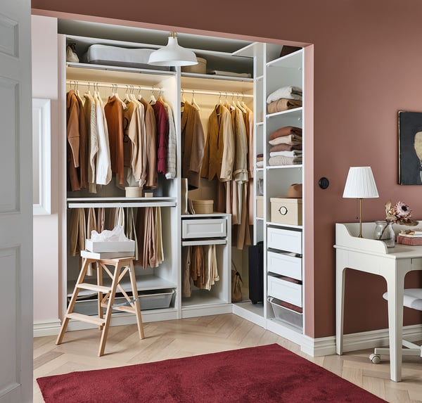 PAX wardrobe with hangers, shelves, and drawers in white, organized clothing and accessories in a bedroom setting.