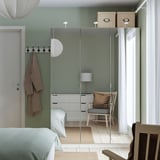Modern bedroom with green PAX wardrobe, mirrors, blue bed, chair, coat hooks, natural light.