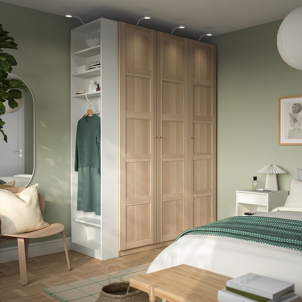 Bedroom with PAX wardrobe in light oak, offering ample storage. Adjacent end-unit with open shelves adds to the minimalist cozy design.