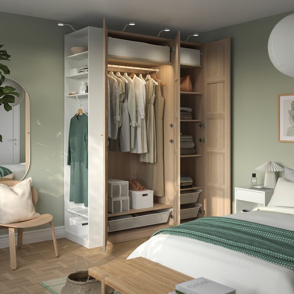 Modern bedroom featuring a PAX wardrobe with hangers, shelves, and organized storage. It efficient space utilization with clothes hanging and folded.