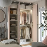 Modern walk-in closet with clothes hangers, shelves, and lighting. Doors are open, revealing organized garments and folded clothes.