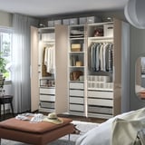 Bedroom with open wardrobe, clothes, and storage.