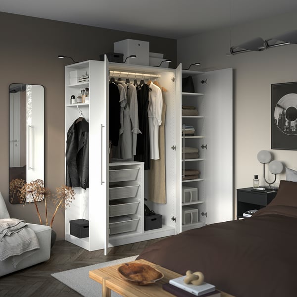 Bedroom featuring a white PAX wardrobe with open doors revealing hanging clothes, drawers, and shelves.