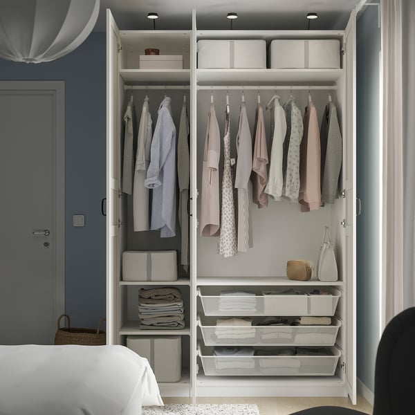 Organized wardrobe with clothes, boxes, and drawers; mirrored doors expand space.