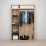 Wooden wardrobe with hanging shirts, folded clothes, and a bag at the bottom.