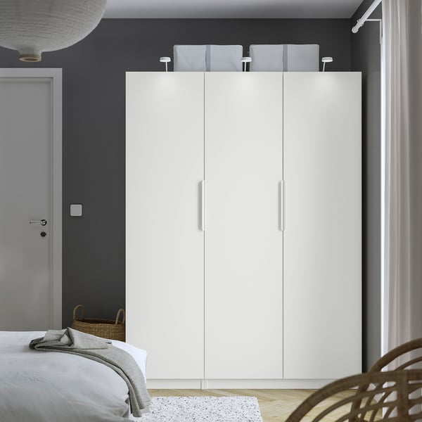 Minimalist bedroom with large white PAX wardrobe, sleek design, clean lines.