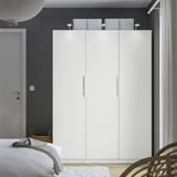 Minimalist bedroom with large white PAX wardrobe, sleek design, clean lines.