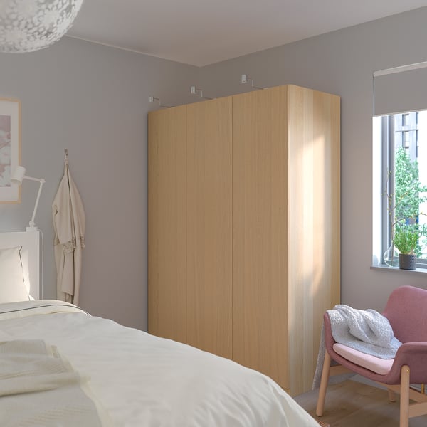 Modern bedroom with large IKEA PAX wardrobe, coat, and plant.