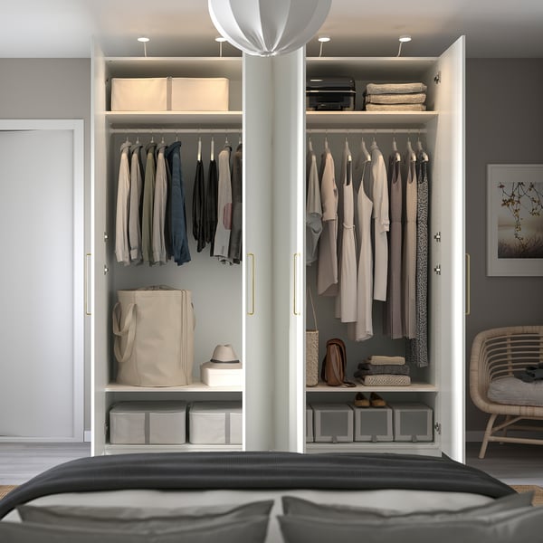 A well-organized wardrobe with clothes on hangers, storage bins, and shelves, featuring integrated lighting and adjustable, dampened hinges.