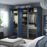 A modern blue PAX wardrobe with shelves, drawers, and hanging space, showing organized clothes and accessories.