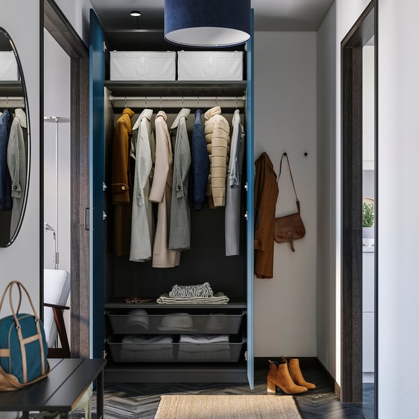 Open wardrobe showcasing coats, bags, and folded clothes with storage baskets, lit by ceiling light.
