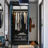 Open wardrobe showcasing coats, bags, and folded clothes with storage baskets, lit by ceiling light.