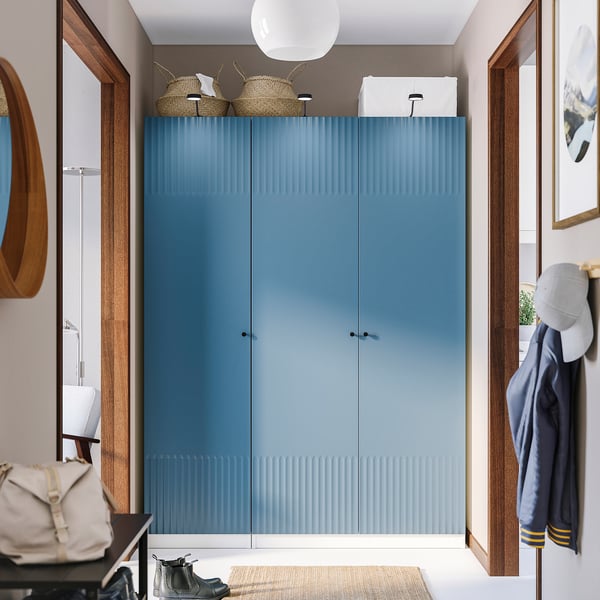 Modern hall with large blue PAX wardrobe, wood accents, hanging jackets, and storage basket.