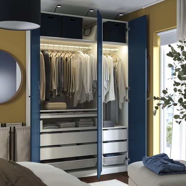 Open wardrobe showcasing organized clothes, drawers, and mesh baskets, featuring integrated lighting and blue doors.