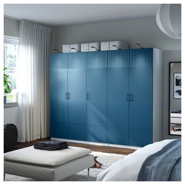 Blue ribbed PAX wardrobe in bedroom with ottoman and bed.