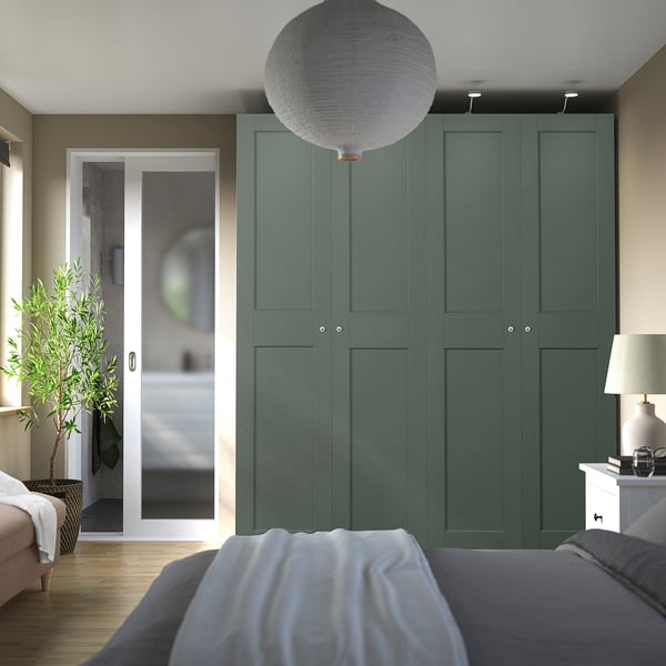 Modern bedroom with tall green PAX wardrobes, pendant lamp, and glass bathroom door.
