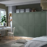 Green PAX wardrobe in bedroom, larger than desk and chair, multiple compartments. Wood floors, rug, and small plant table.