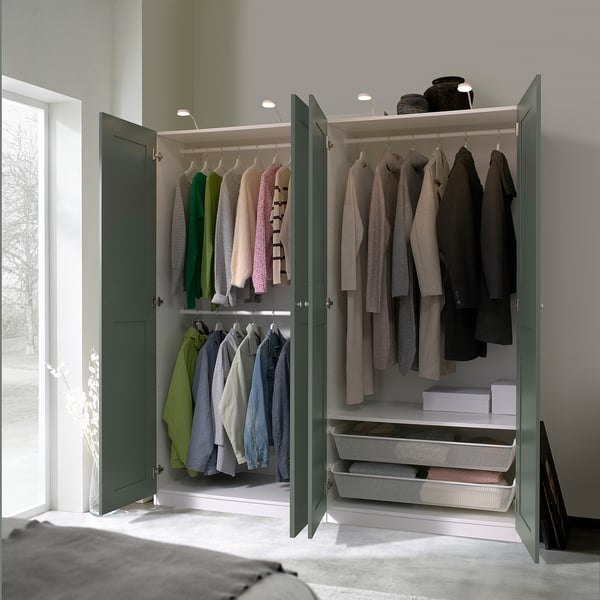 Open wardrobe showing clothes, accessories, and drawers. Interior lighting illuminates contents.