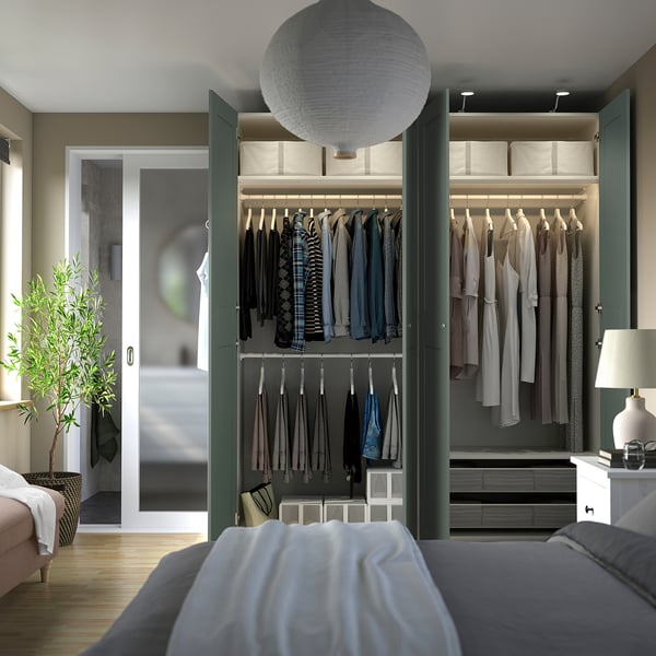 Modern bedroom with open walk-in closet displaying clothes, shelves, and storage drawers, featuring soft lighting and integrated organization.