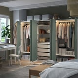 Open closet showing organized clothes and storage bins, with green doors and integrated lighting.