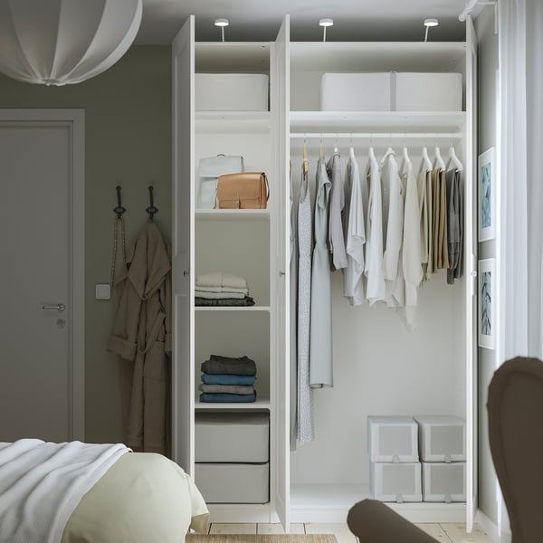 Minimalist PAX wardrobe with clothes and storage near bed.
