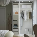 Minimalist PAX wardrobe with clothes and storage near bed.