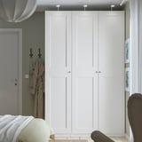 Minimalist bedroom with large white PAX wardrobe, silver knobs, grey door, and partially visible bed.