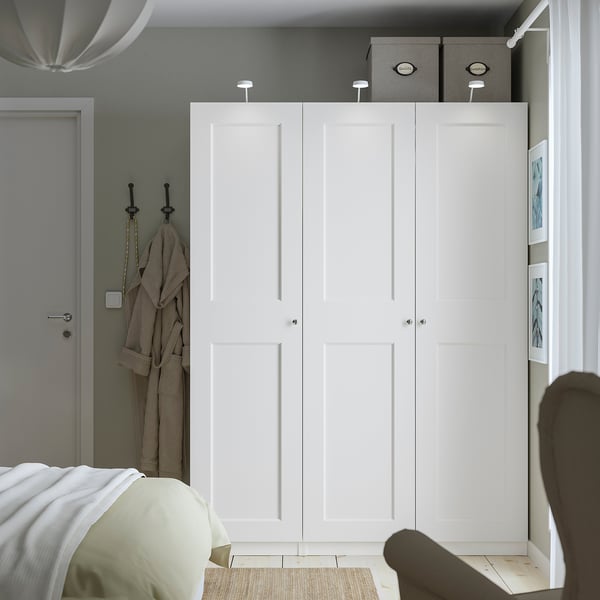Minimalist bedroom with PAX wardrobe, storage boxes, coat, bed, and pendant light.