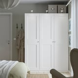 Minimalist bedroom with PAX wardrobe, storage boxes, coat, bed, and pendant light.