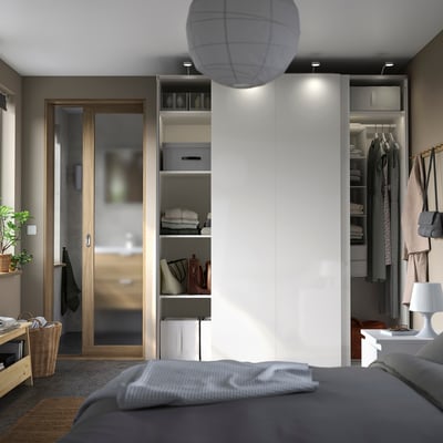 Modern bedroom with white PAX wardrobe, sliding doors, open shelves, gray bed, and wooden bench.