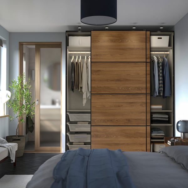 Modern wooden wardrobe with sliding doors revealing neatly organised clothes and shelves. Soft-close mechanism and hanging storage visible.