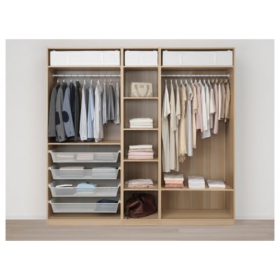Open wooden PAX wardrobe showing hangers with shirts, folded clothes on shelves, and mesh baskets.