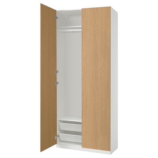 An open white and light wood-colored PAX wardrobe with shelves and drawers.