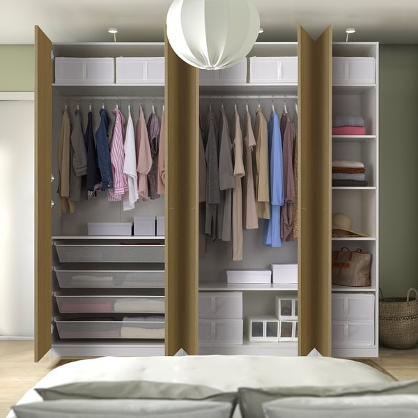 Modern walk-in closet with clothes and storage shelves, lit by hanging lamps.