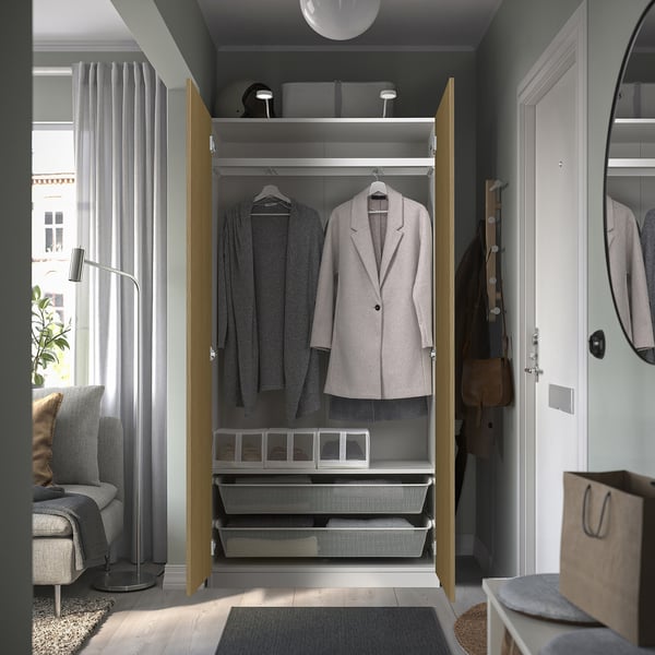 Open wardrobe displaying clothes, shelves, and drawers in a well-lit room.