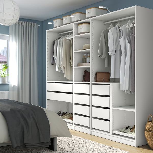 IKEA PAX wardrobe with clothes and accessories. Drawers, shelves, and hanging space, neatly fitting next to a bed.