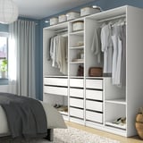 IKEA PAX wardrobe with clothes and accessories. Drawers, shelves, and hanging space, neatly fitting next to a bed.